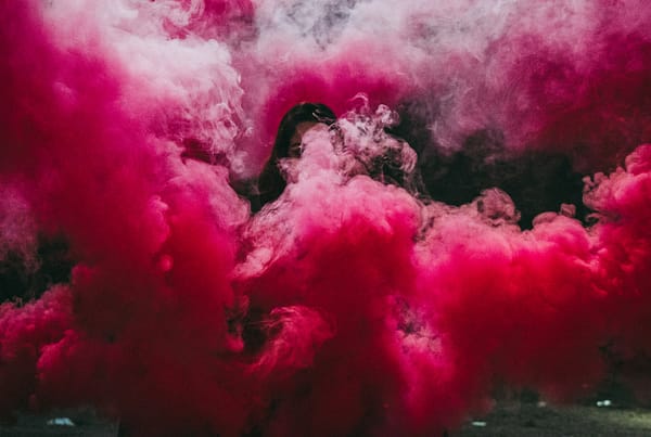 Girl surrounded by dark pink smoke.