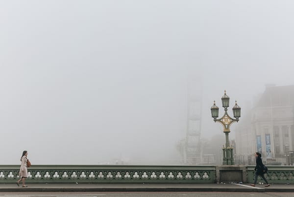 2 women walking across a foggy bridge in Westminster.