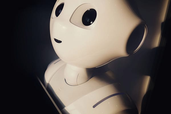 A white robot with black eyes looking upwards in a dark room.