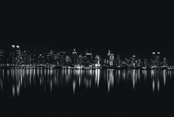 City skyline at night behind reflective water.